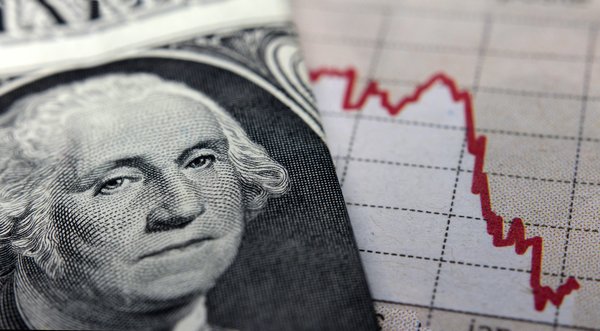 George Washington's face prominently featured on a one dollar bill that's next to a falling chart.