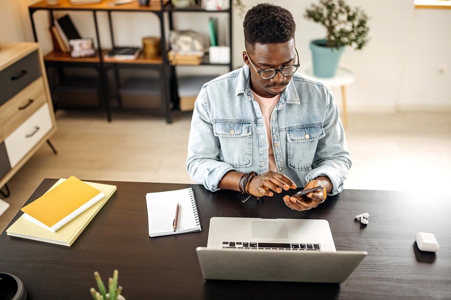 A man sitting at a desk using his phone.