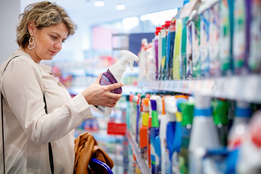 A person selecting cleaning spray at a grocery store.