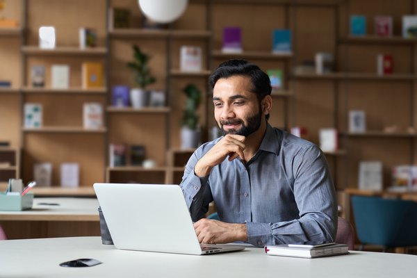 Smiling person working on laptop in modern office.